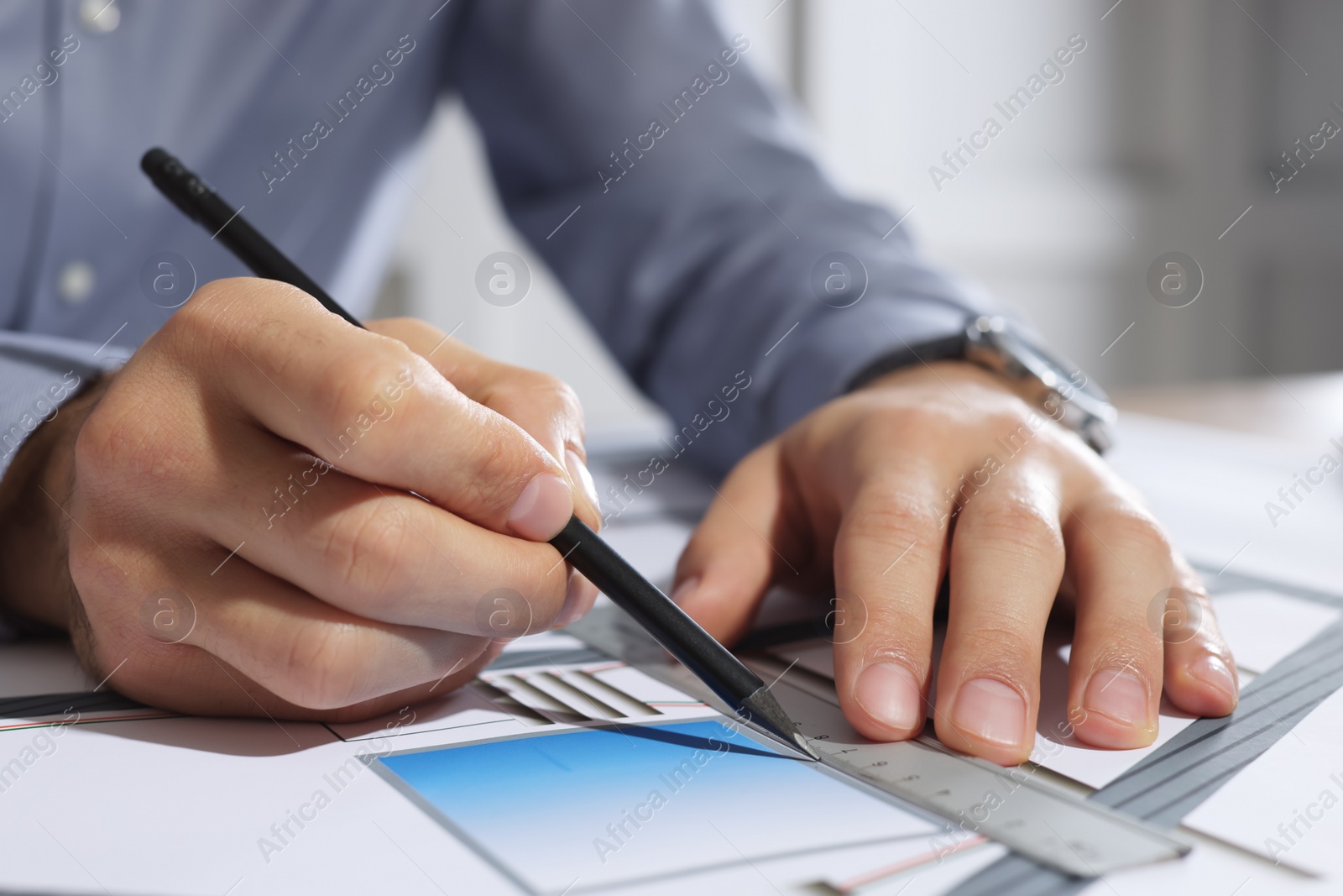 Photo of Architect working with construction drawings indoors, closeup