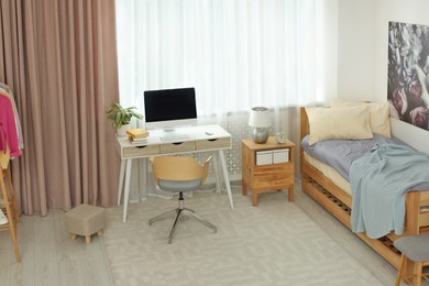 Stylish teenager's room interior with computer and comfortable bed