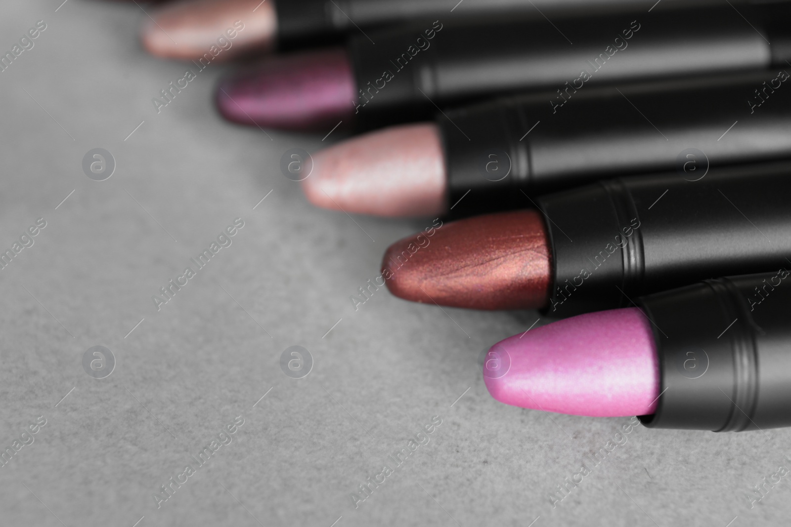 Photo of Set of bright lipsticks on grey background. Space for text