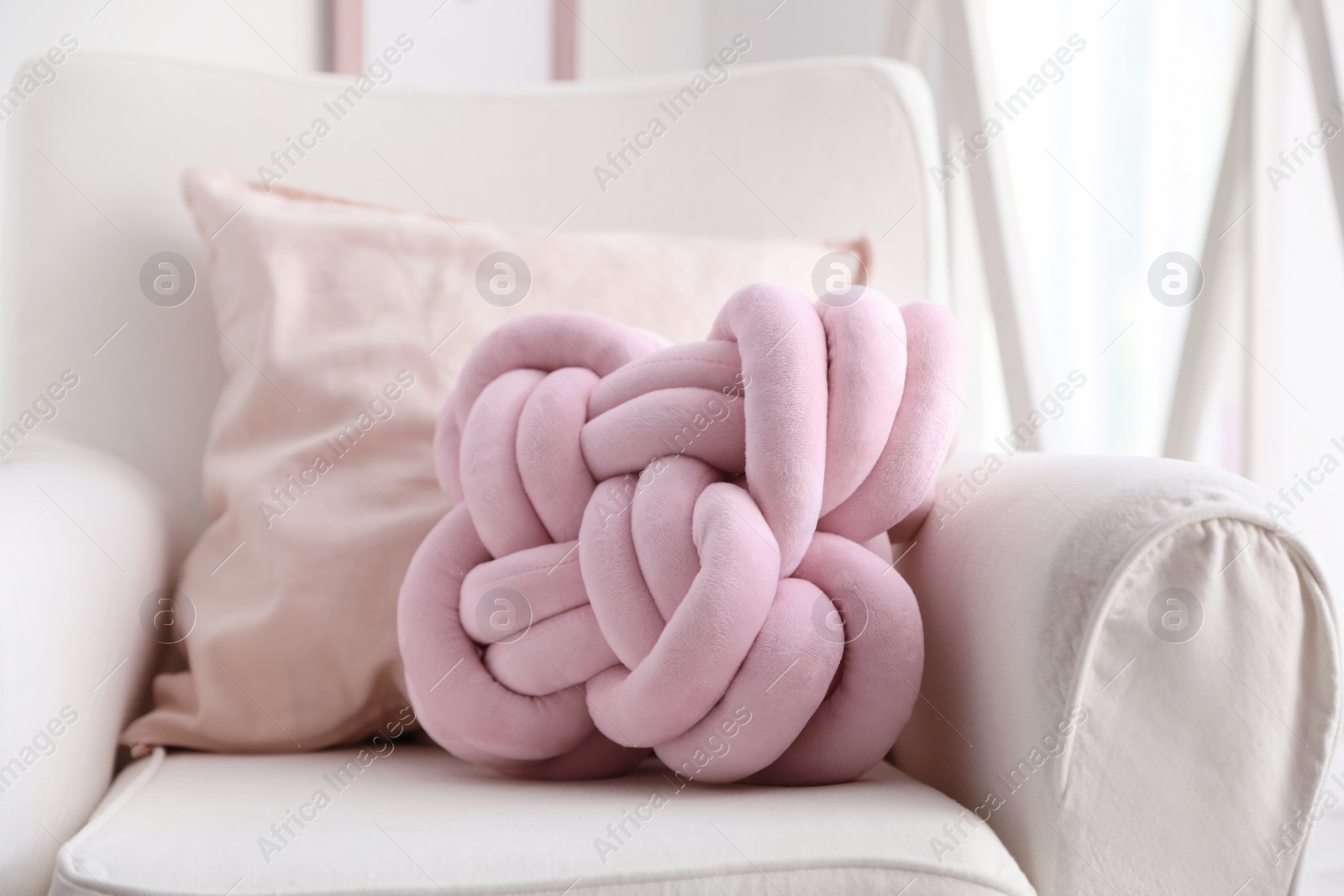 Photo of Pillows on light armchair indoors. Unusual cushion design