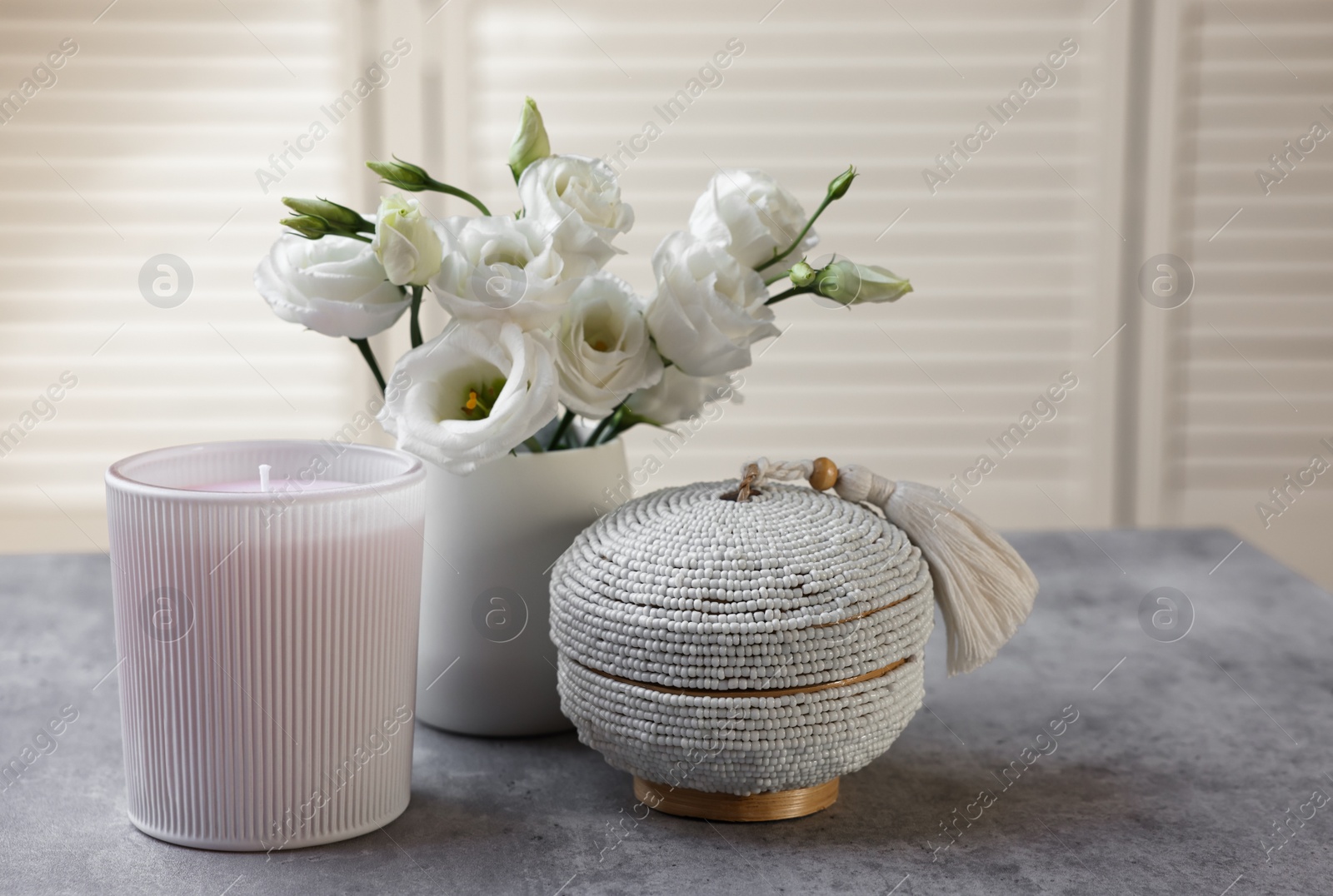 Photo of Scented candle, box and eustoma flowers on gray marble table