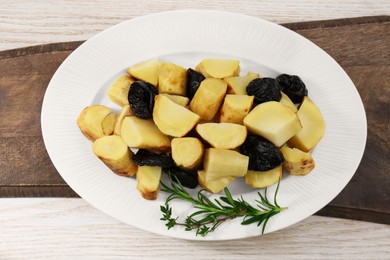 Tasty homemade parsnips with prunes and rosemary on white wooden table, top view