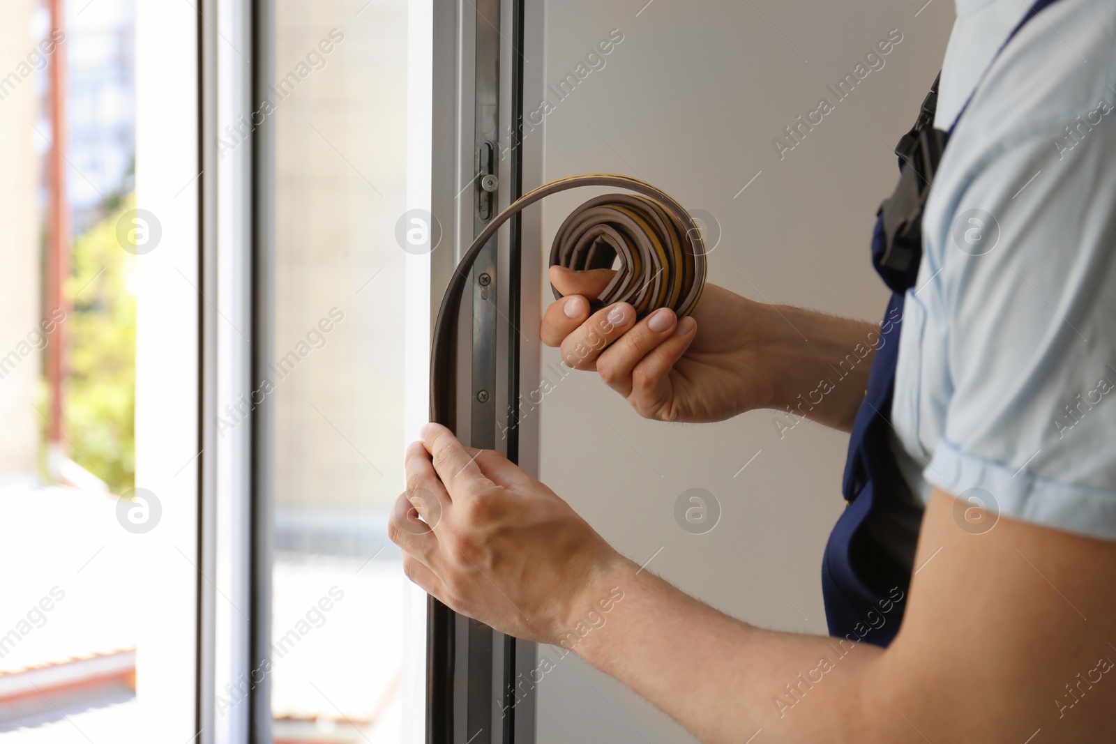 Photo of Construction worker putting sealing foam tape on window indoors