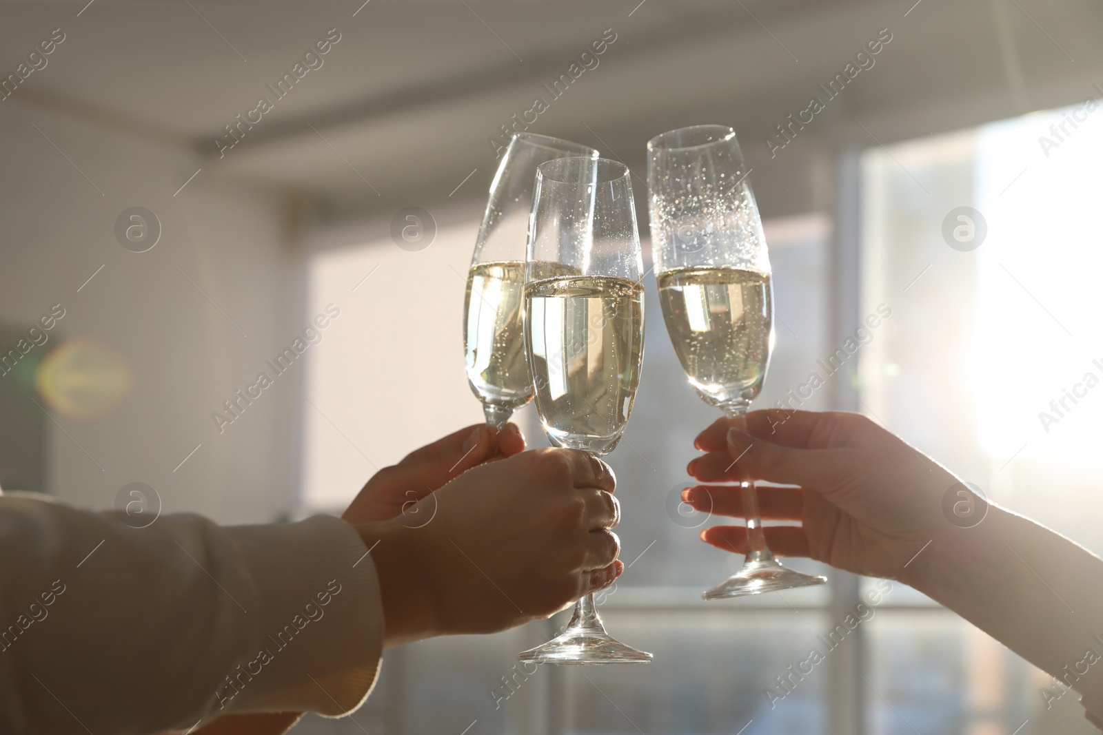 Photo of People clinking glasses of champagne in office, closeup. Holiday cheer and drink