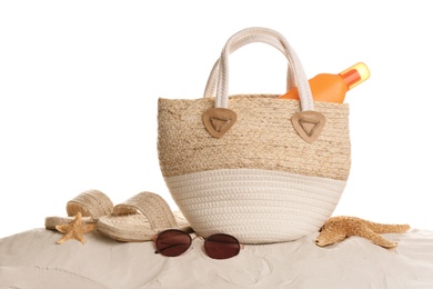 Stylish bag and different beach accessories on sand against white background