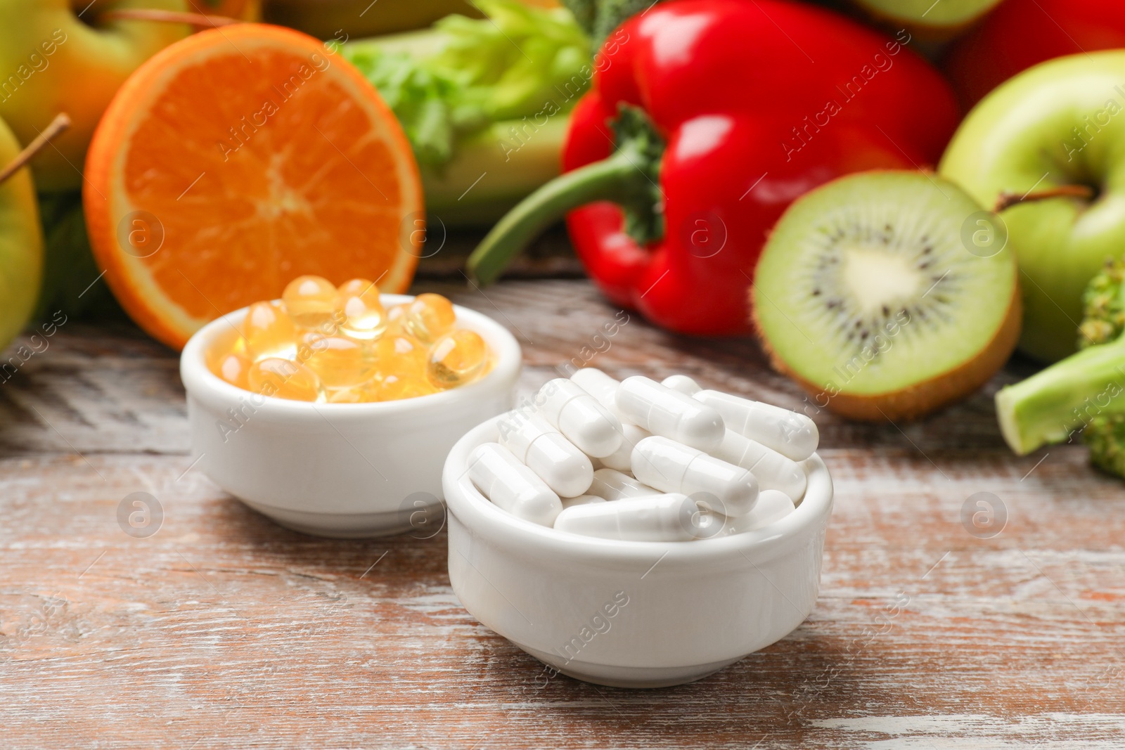 Photo of Dietary supplements. Different pills in bowls and food products on wooden table