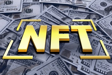 Image of Golden abbreviation NFT (non-fungible token) over dollar banknotes