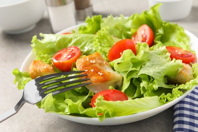 Eating delicious salad with chicken and cherry tomato at table, closeup