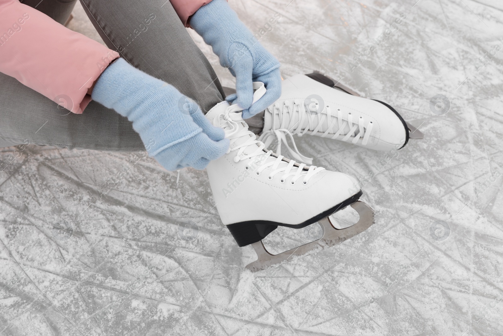 Photo of Woman lacing figure skates on ice, closeup