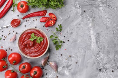 Photo of Flat lay composition with organic ketchup in bowl on grey textured table, space for text. Tomato sauce