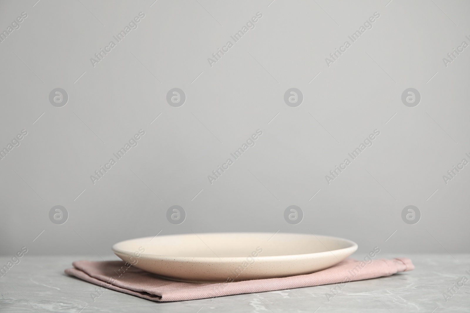 Photo of Empty plate and pink towel on light grey marble table. Space for text