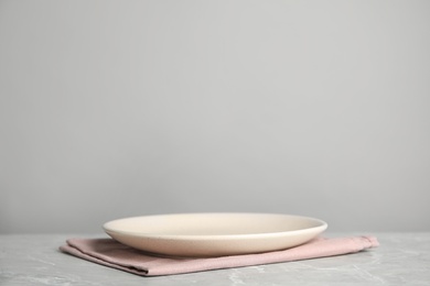 Photo of Empty plate and pink towel on light grey marble table. Space for text