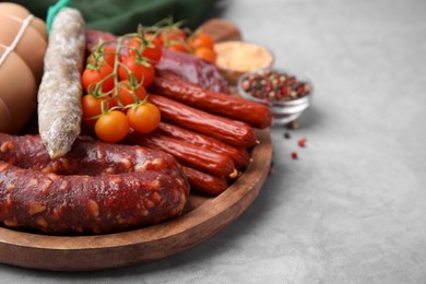 Photo of Different types of tasty sausages and ingredients on light grey table, closeup. Space for text