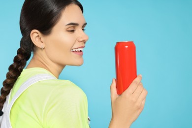 Photo of Beautiful happy woman holding red beverage can on light blue background