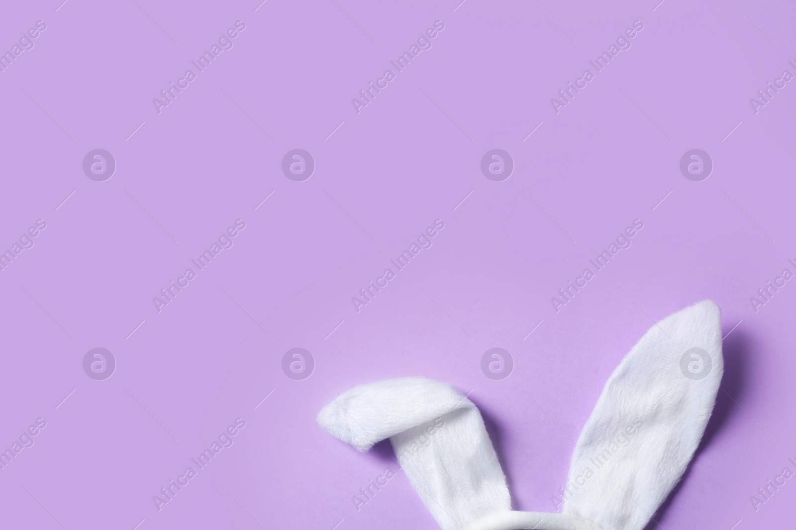 Photo of Funny Easter bunny ears on color background, top view with space for text