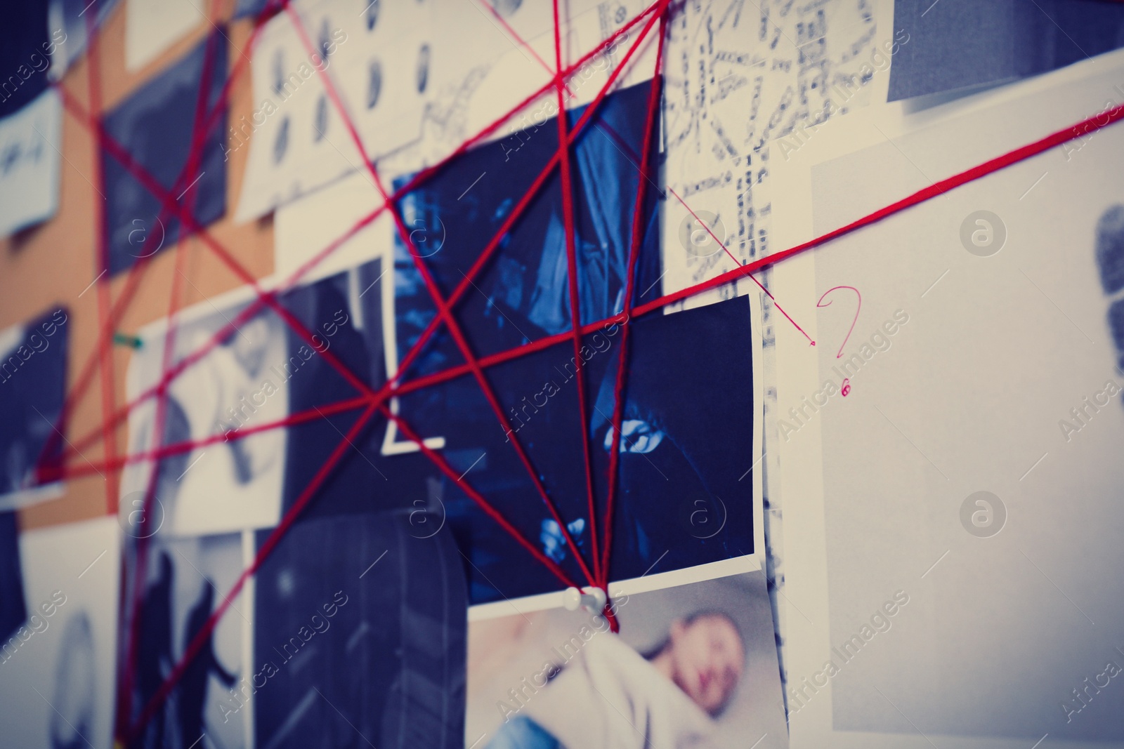 Photo of Detective board with crime scene photos and red threads, closeup