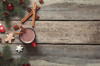 Photo of Flat lay composition of delicious hot chocolate with cinnamon and Christmas decor on wooden table, space for text