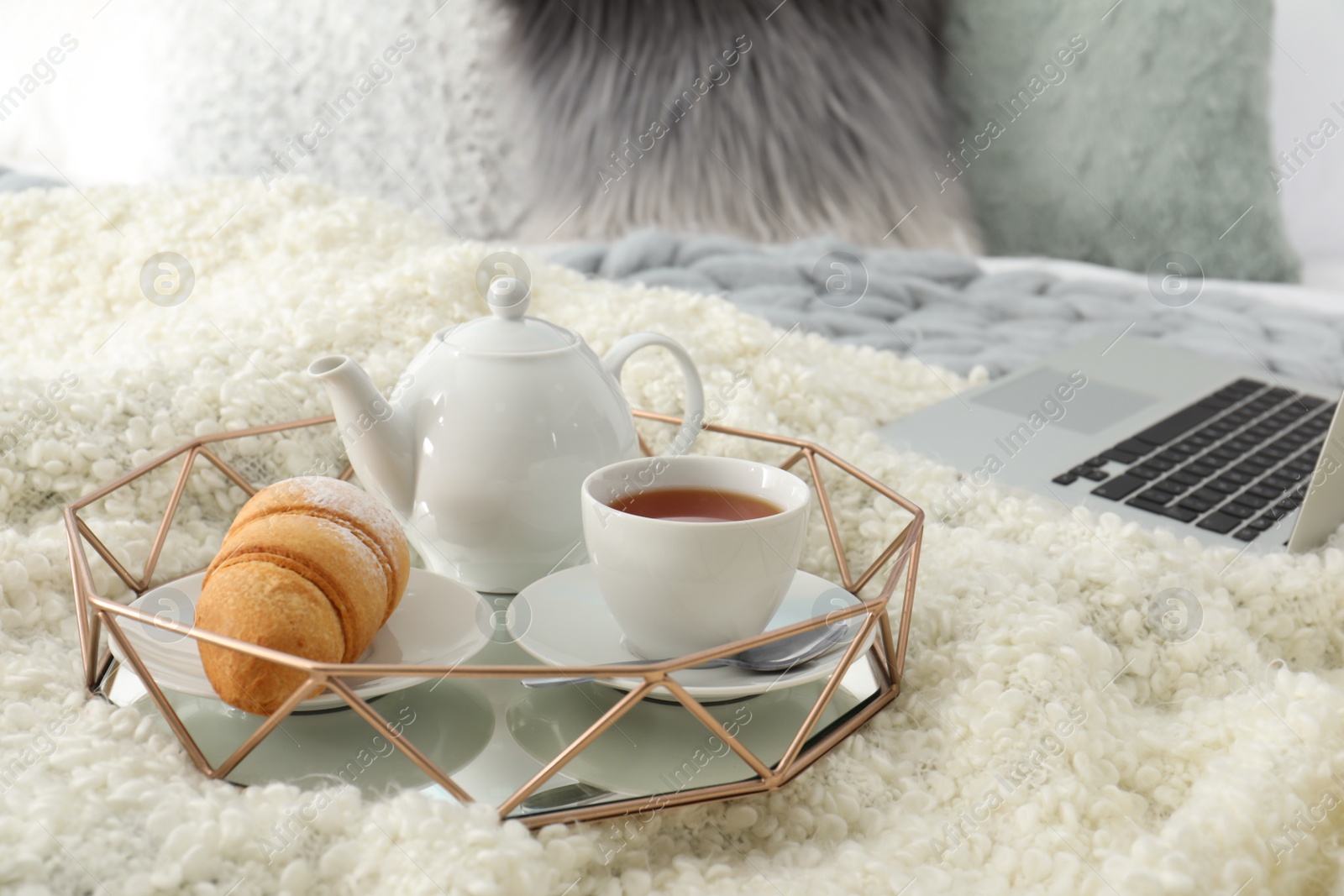 Photo of Tray with tasty breakfast and laptop on bed