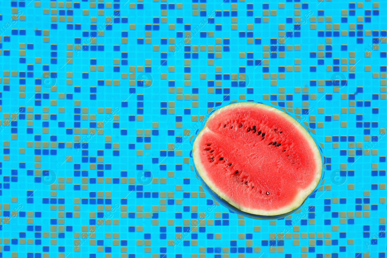 Photo of Half of fresh juicy watermelon in swimming pool, top view. Space for text