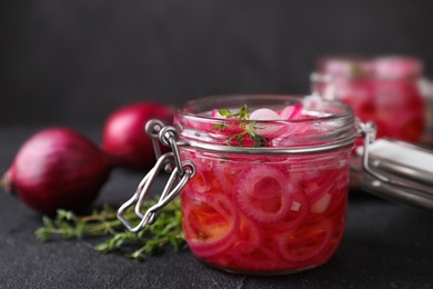 Jar with tasty pickled onions on black table