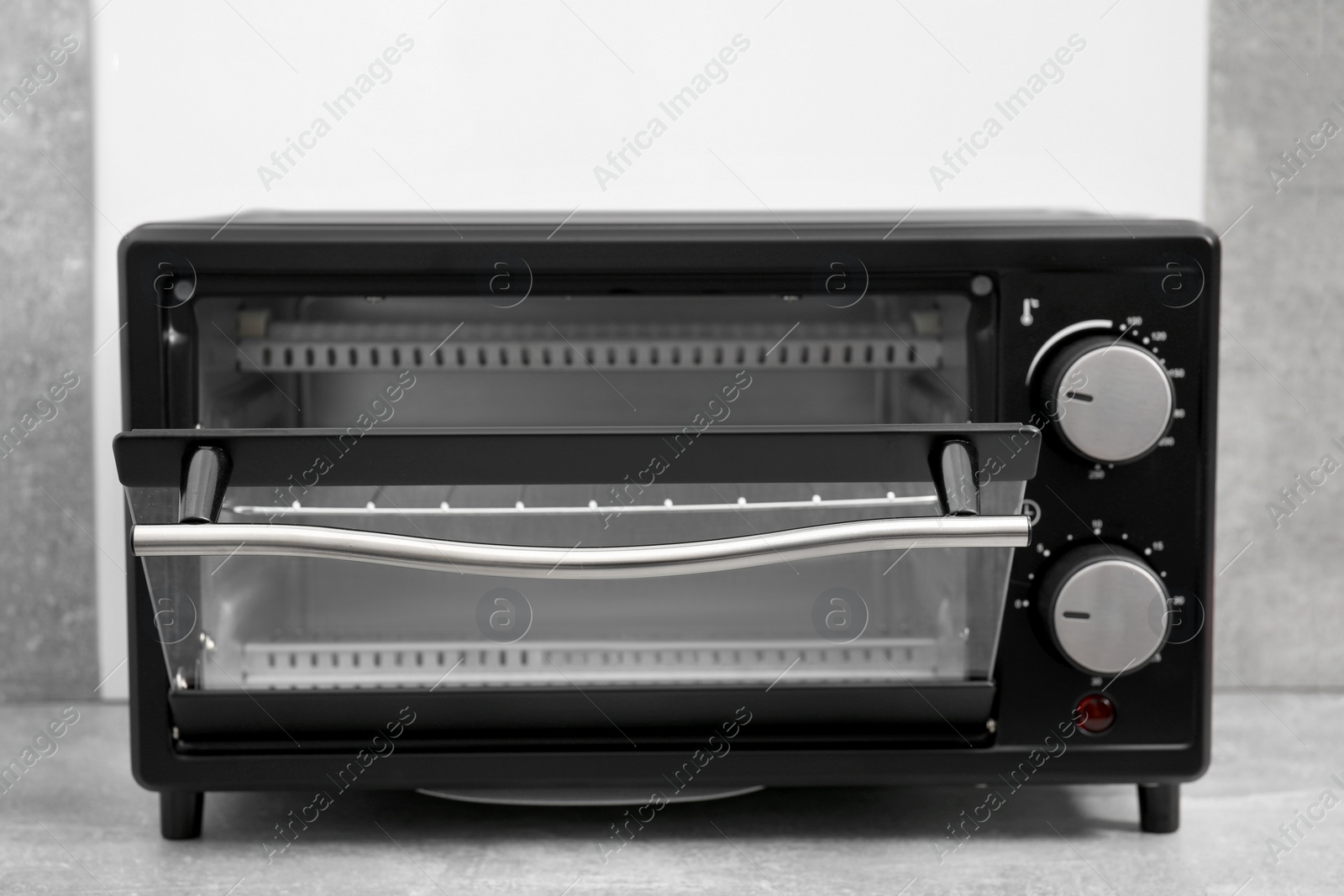 Photo of One electric oven on light grey table, closeup. Cooking appliance