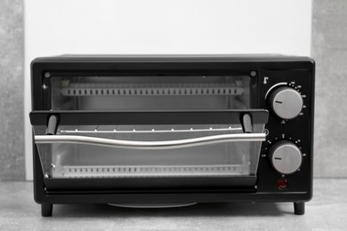 Photo of One electric oven on light grey table, closeup. Cooking appliance