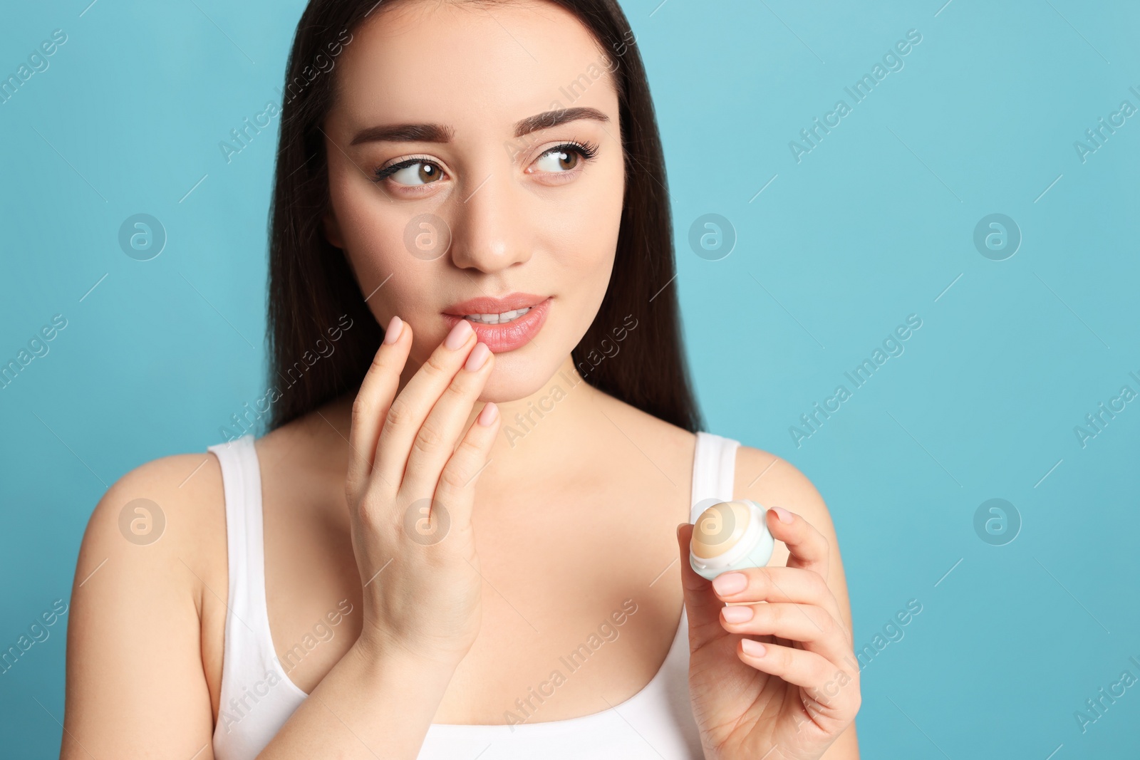 Photo of Young woman with lip balm on turquoise background