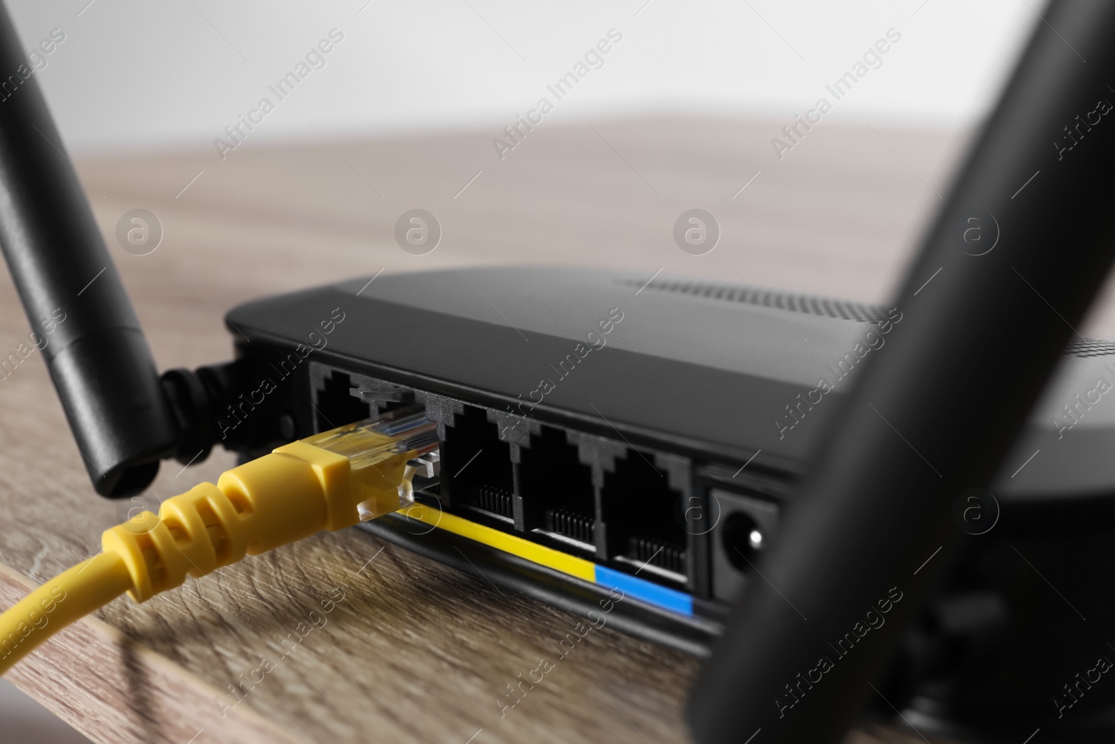 Photo of Connected cable to router on wooden table, closeup. Wireless internet communication