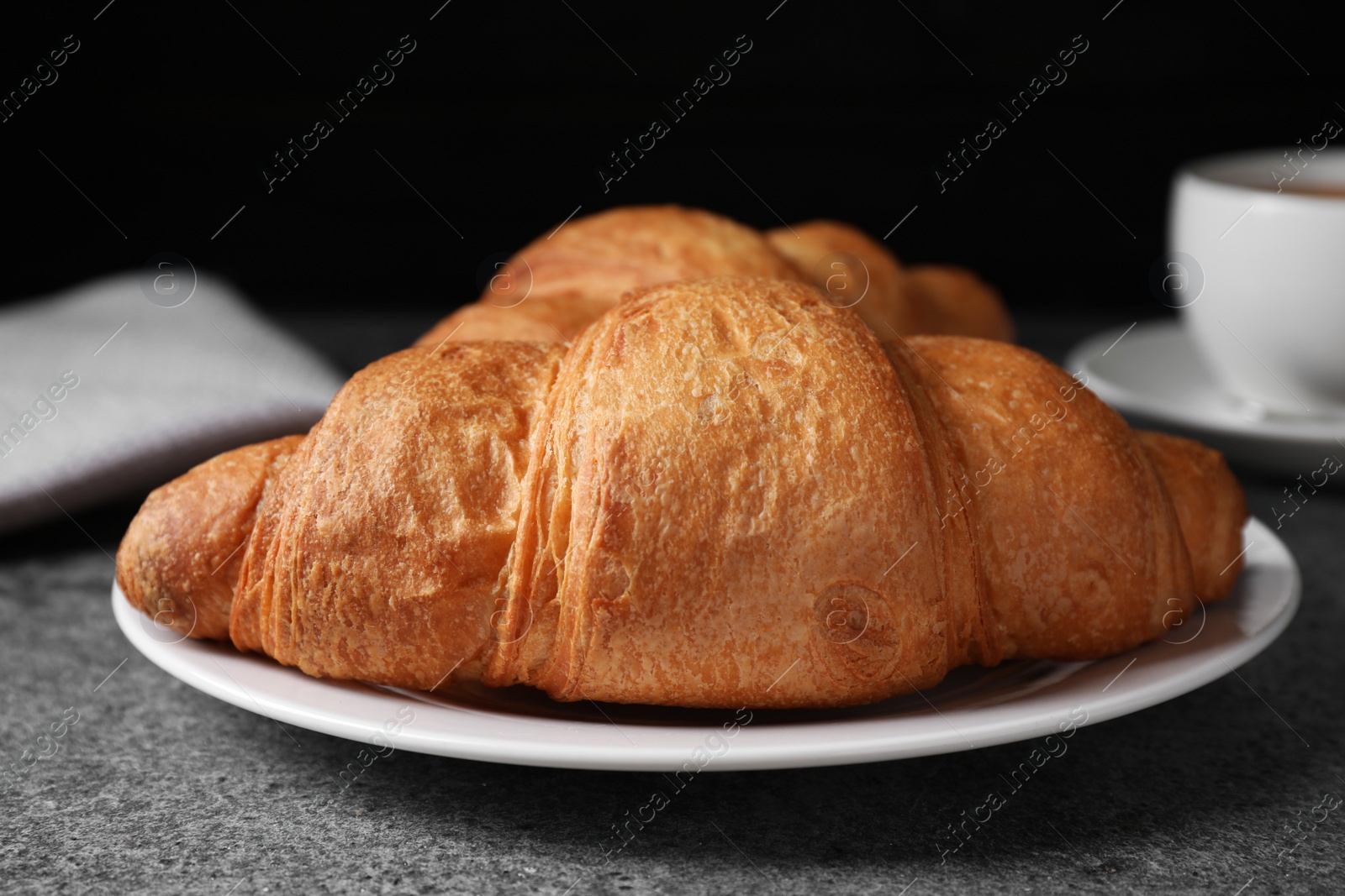 Photo of Tasty fresh croissants on grey table, closeup