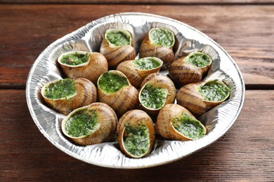 Delicious cooked snails on wooden table, closeup