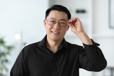 Portrait of smiling businessman in glasses indoors