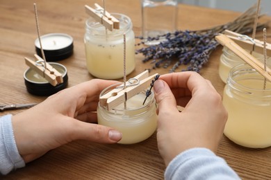 Photo of Woman making aromatic candles at wooden table, closeup