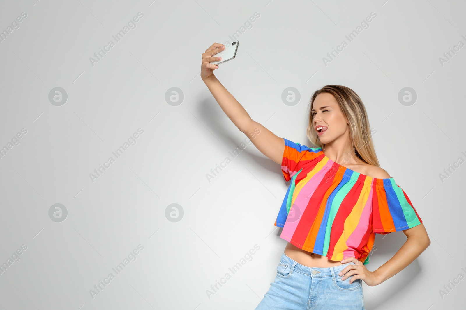 Photo of Beautiful woman taking selfie on light background