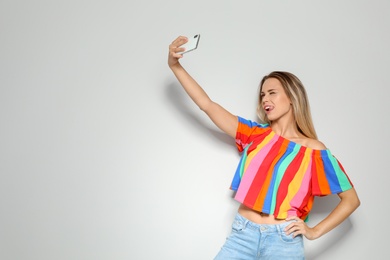 Photo of Beautiful woman taking selfie on light background