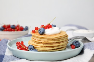 Photo of Tasty pancakes with natural yogurt, blueberries and red currants on table