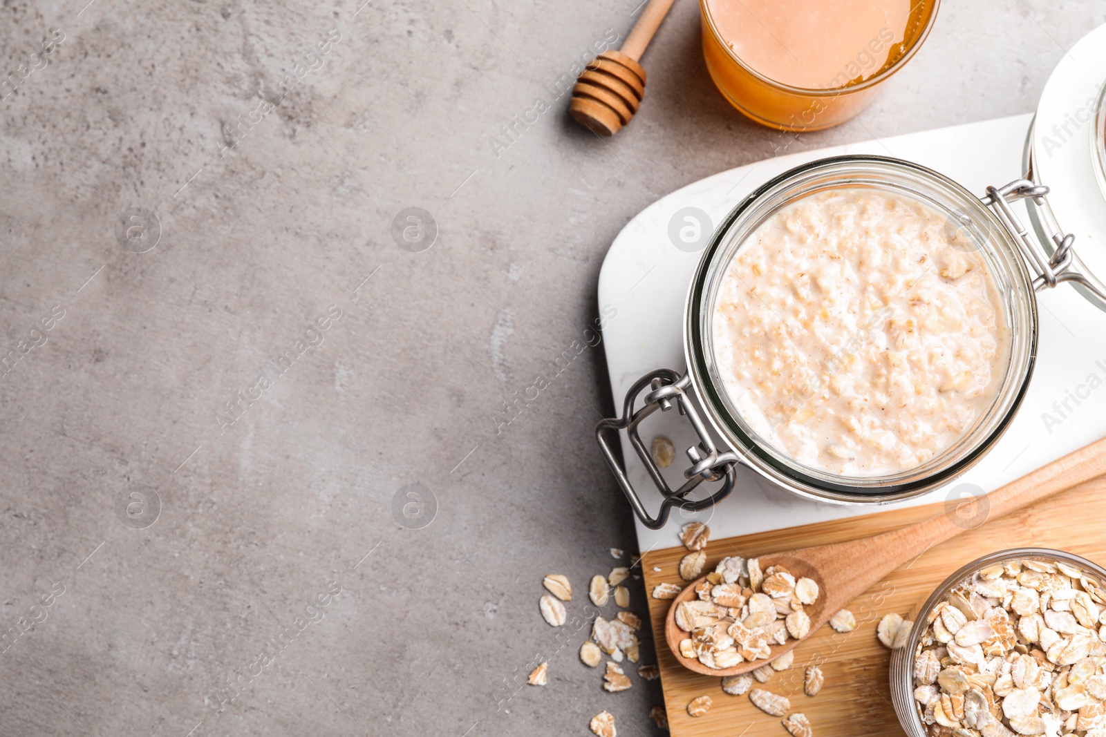 Photo of Handmade face mask, oatmeal and honey on grey table, flat lay. Space for text