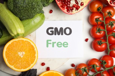 Tasty fresh GMO free products and paper card on white table, flat lay