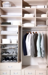 Photo of Stylish clothes, shoes and home stuff in large wardrobe closet