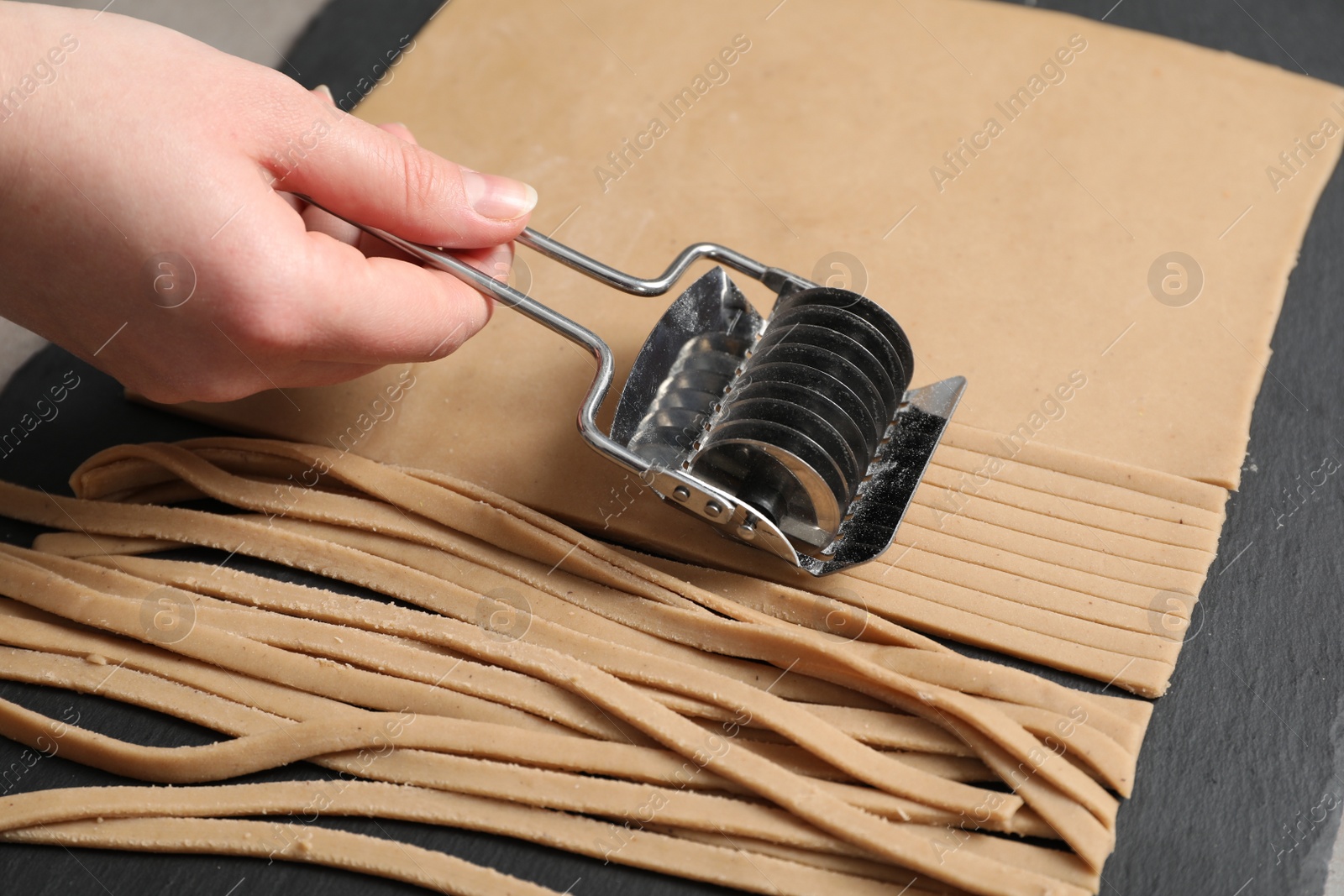 Photo of Woman cutting dough for soba at table, closeup