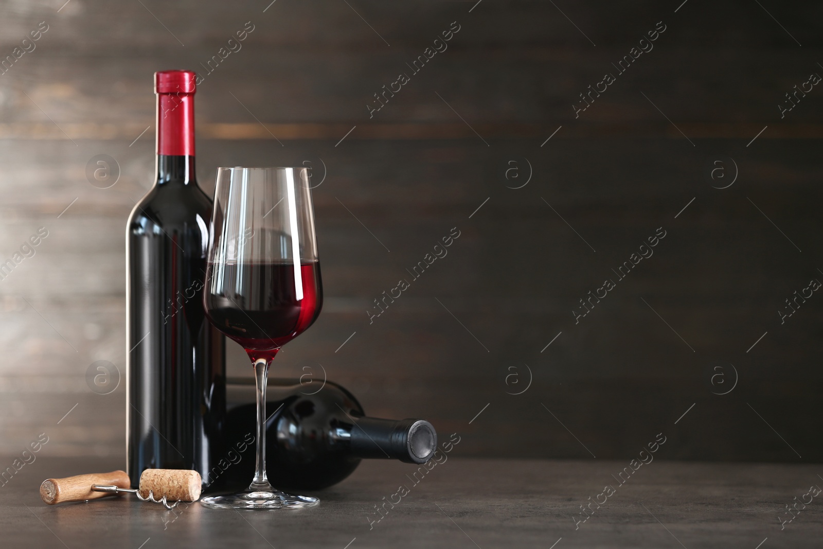 Photo of Composition with glass and bottles of red wine on table. Space for text