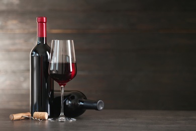 Composition with glass and bottles of red wine on table. Space for text