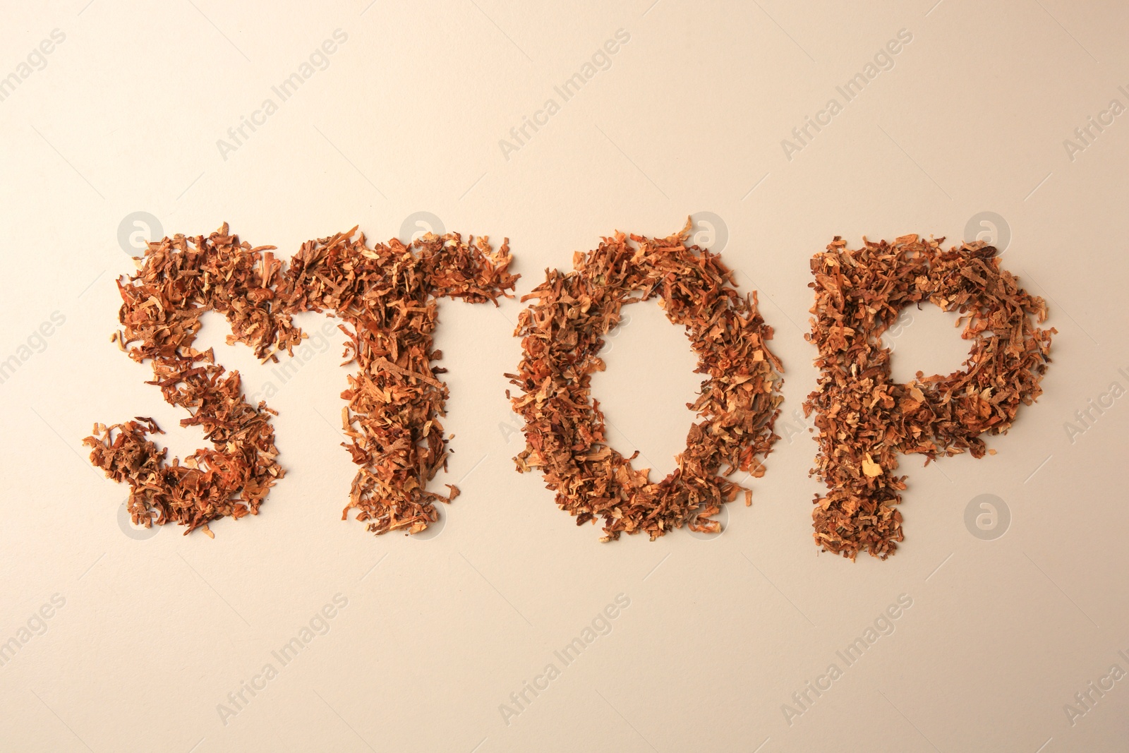 Photo of Word Stop made of dry tobacco on beige background, flat lay. Quitting smoking concept