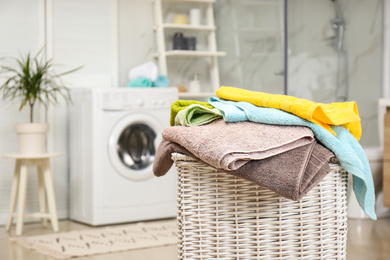 Photo of Wicker basket with laundry and washing machine in bathroom. Space for text