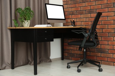 Stylish office interior with comfortable chair, desk and computer