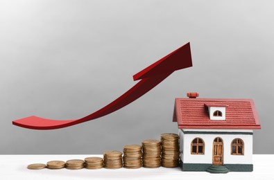 Image of Mortgage concept. House model and coins on white wooden table against light grey background 