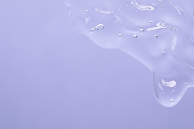Transparent cleansing gel on violet background, top view with space for text. Cosmetic product