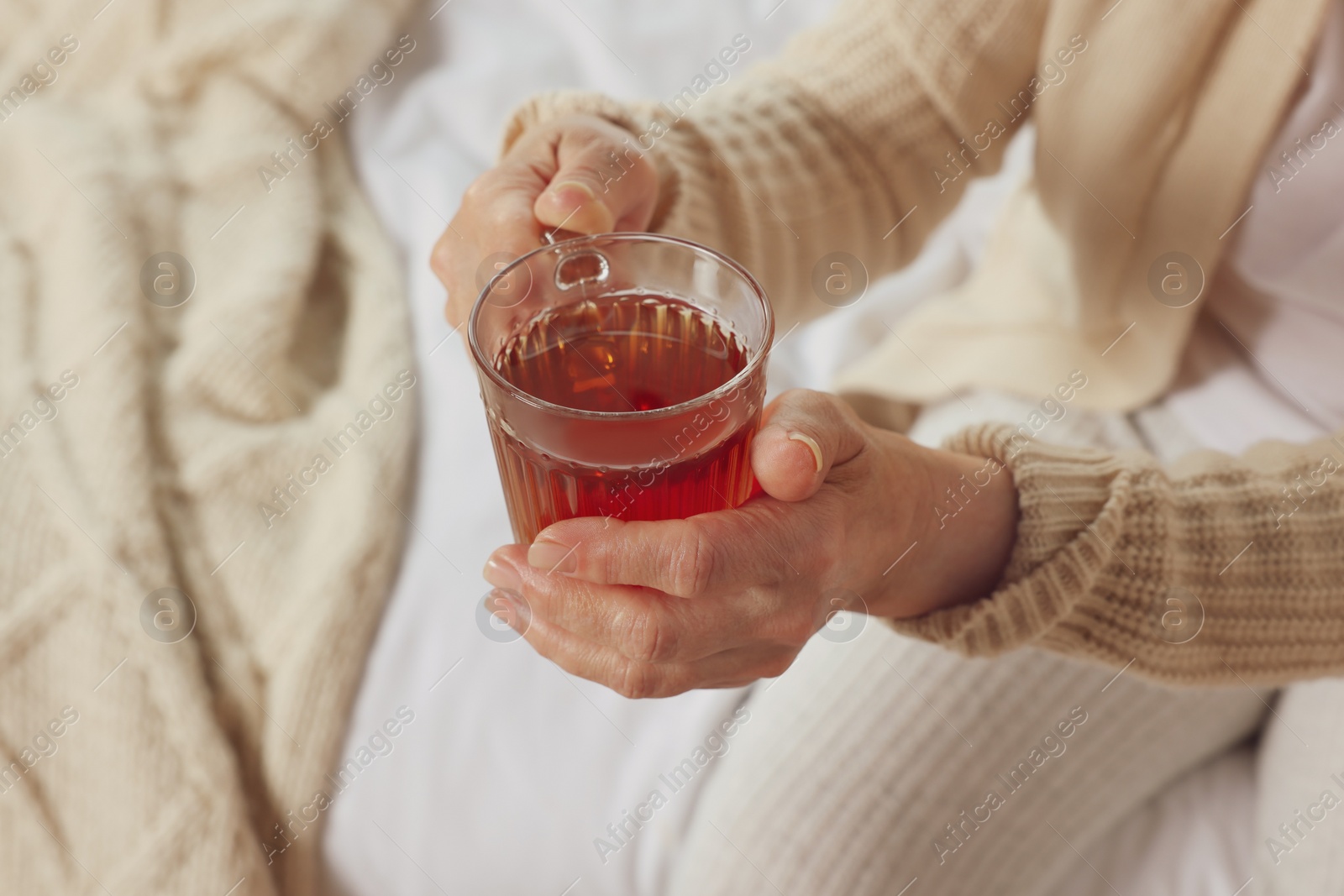 Photo of Elderly woman with cup of hot tea indoors, closeup. Home care service