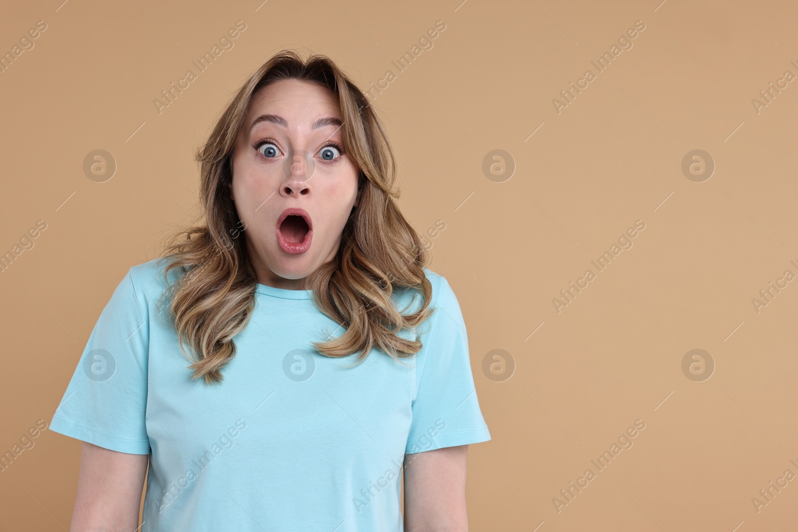 Photo of Portrait of surprised woman on beige background. Space for text