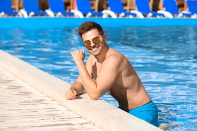 Handsome young man at swimming pool edge on sunny day