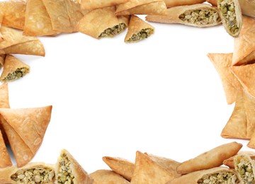 Frame made of crispy delicious samosas on white background